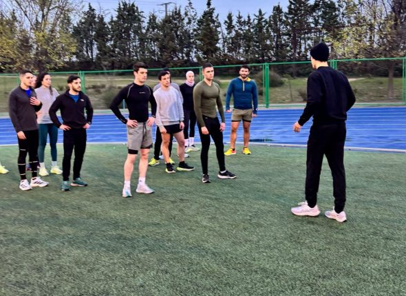 Preparador S4S explicando estrategia a opositores en pista de atletismo