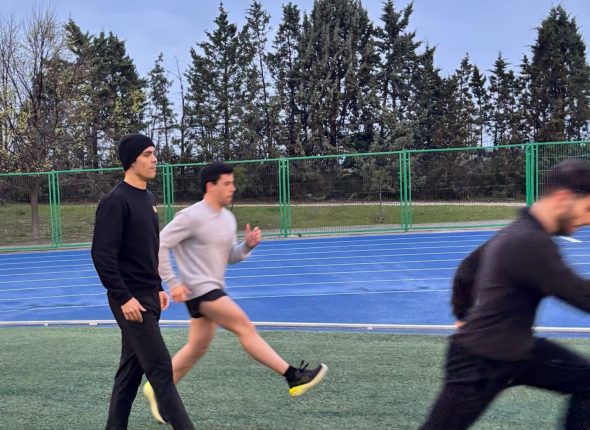 Preparador de S4S supervisando un sprint en pista de atletismo, contexto donde aparece la sobrecarga del tendón de Aquiles