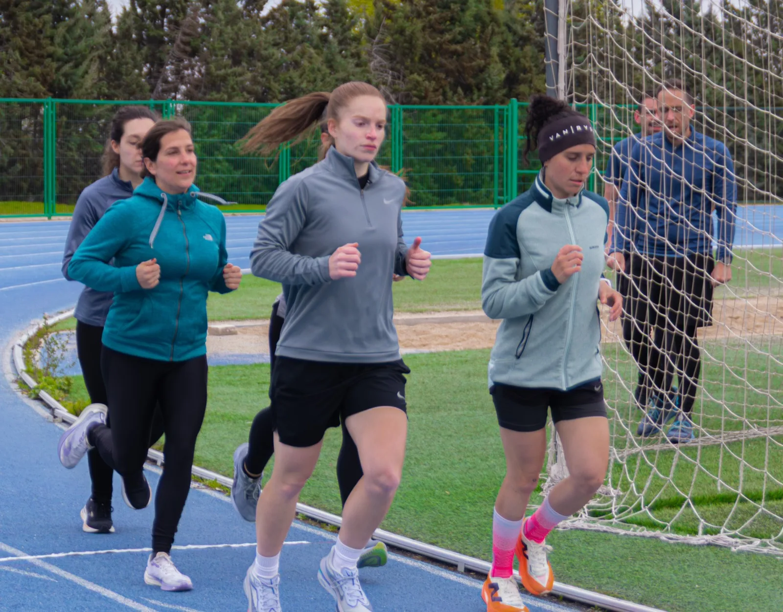 Grupo de opositoras a Policía Nacional trotando en la curva de la pista de atletismo durante una sesión de S4S Preparación Física