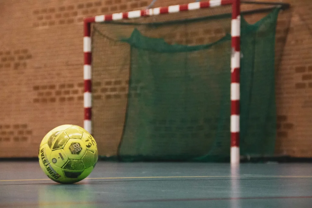 Balón de fútbol sala ante una portería en pista cubierta