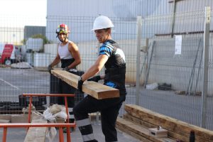 Dos opositores de bomberos de S4S transportando un madero durante un entrenamiento de oficios